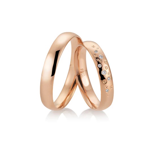 Zwei Ringe aus Roségold, ein schlichter und ein mit kleinen weißen Diamanten besetzter, auf weißem Grund - perfekte Accessoires für exklusive Brautmode und moderne Brautkleider in Aalen.