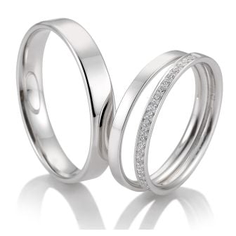 Zwei silberne Eheringe, einer schlicht und einer mit einer Reihe kleiner Diamanten, auf weißem Grund - perfekt für Paare in Stuttgart oder der Schweiz, die ihre modernen Brautkleider mit moderner Eleganz ergänzen möchten.